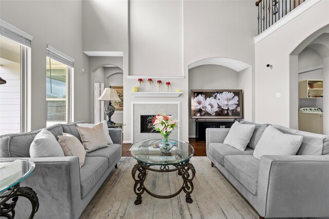 22726 Little Blue Stem Dr, Tomball, TX 77375 - living room featuring a tile fireplace, a high ceiling, washer / clothes dryer, and arched walkways