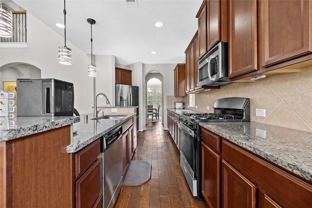 22726 Little Blue Stem Dr, Tomball, TX 77375 - kitchen featuring a sink, tasteful backsplash, dark wood finished floors, arched walkways, and appliances with stainless steel finishes