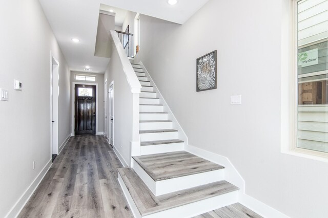 foyer featuring stairway, wood finished floors, baseboards, and recessed lighting