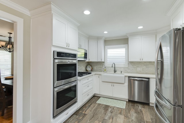11107 Atwell Dr, Houston, TX 77096 - kitchen featuring appliances with stainless steel finishes, a sink, crown molding, wood finished floors, and light countertops