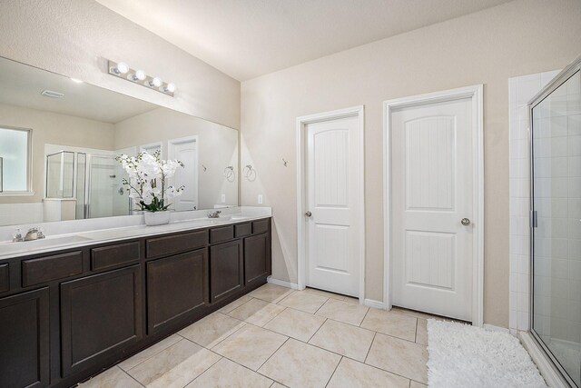 bathroom featuring a shower stall, tile patterned flooring, and double vanity