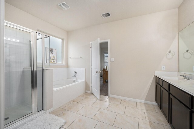 full bathroom featuring a shower stall, a bath, vanity, and tile patterned floors