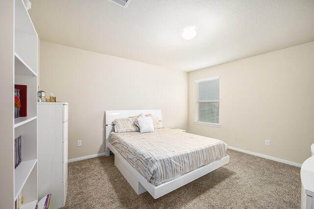 carpeted bedroom featuring baseboards and a textured ceiling