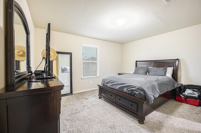 bedroom with light carpet, baseboards, and a textured ceiling