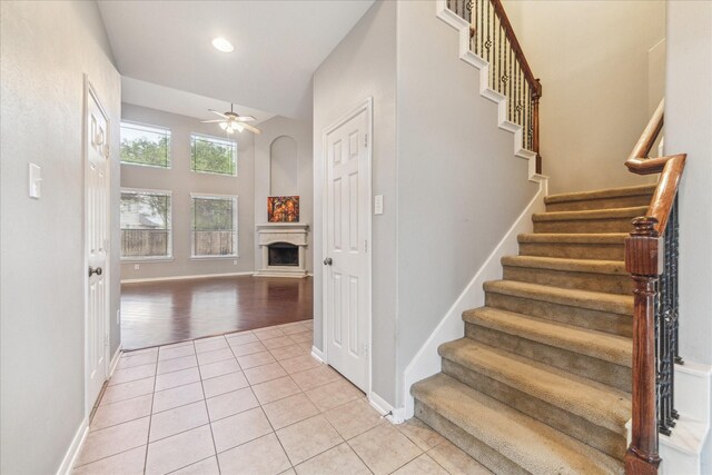 stairs with a fireplace, a ceiling fan, tile patterned floors, baseboards, and recessed lighting