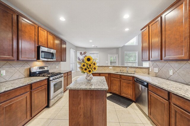 kitchen with stainless steel appliances, a sink, decorative backsplash, recessed lighting, and a center island