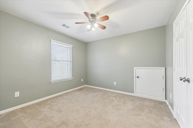 spare room with ceiling fan, light carpet, and baseboards