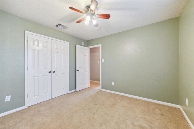 unfurnished bedroom with light colored carpet, baseboards, a closet, and ceiling fan