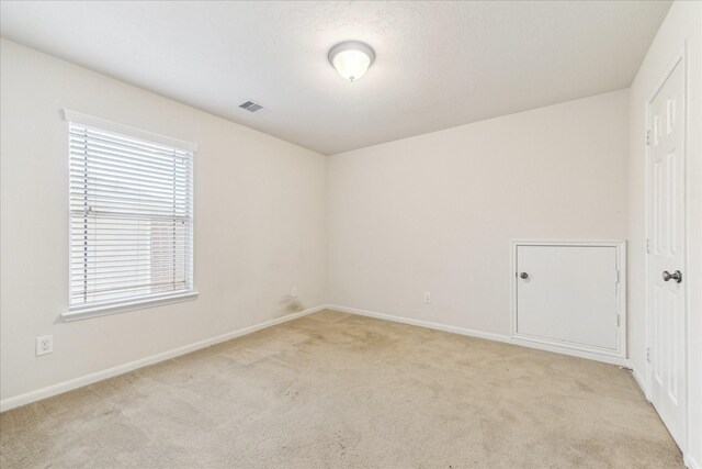 spare room featuring light carpet, healthy amount of natural light, and baseboards