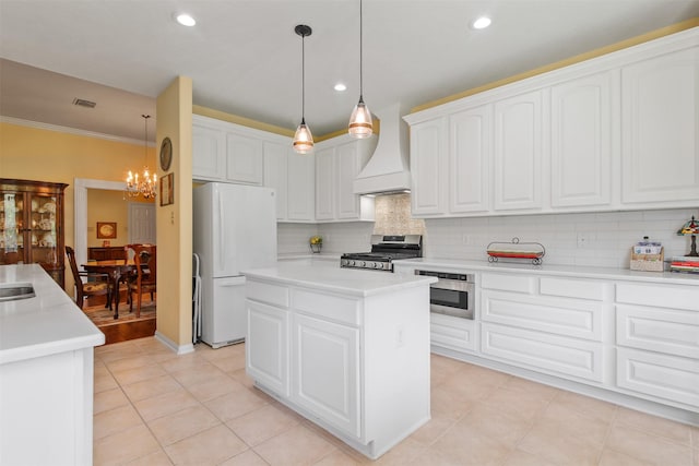 kitchen with appliances with stainless steel finishes, custom range hood, a center island, a chandelier, and tasteful backsplash