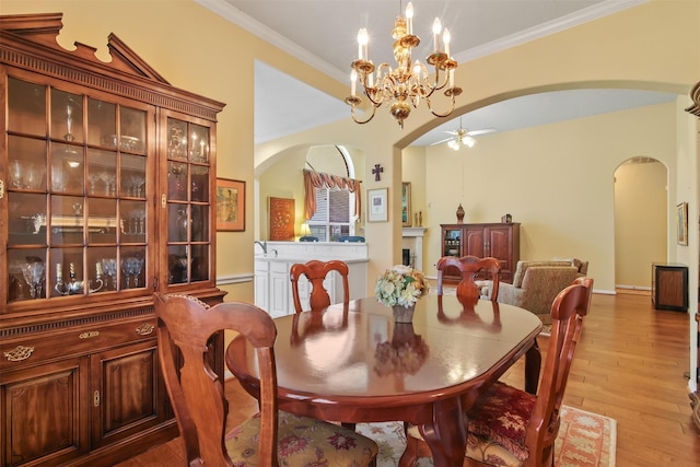 dining room featuring arched walkways, wood finished floors, a ceiling fan, crown molding, and a chandelier