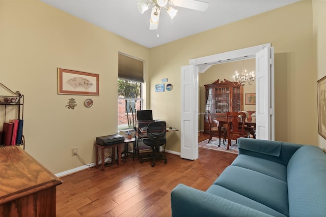office space with a chandelier, ceiling fan, wood finished floors, and baseboards