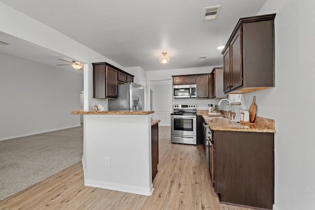 13228 Miller Ln, Willis, TX 77318 - kitchen with appliances with stainless steel finishes, dark brown cabinets, a sink, and a ceiling fan