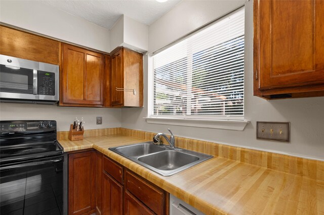 kitchen featuring stainless steel microwave, black range with electric cooktop, a sink, and light countertops