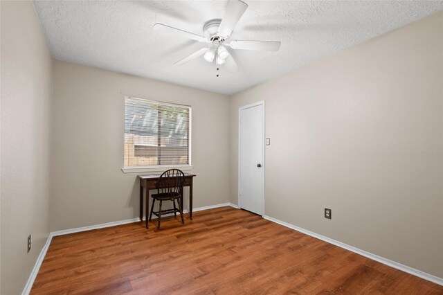 spare room with wood finished floors, baseboards, a ceiling fan, and a textured ceiling