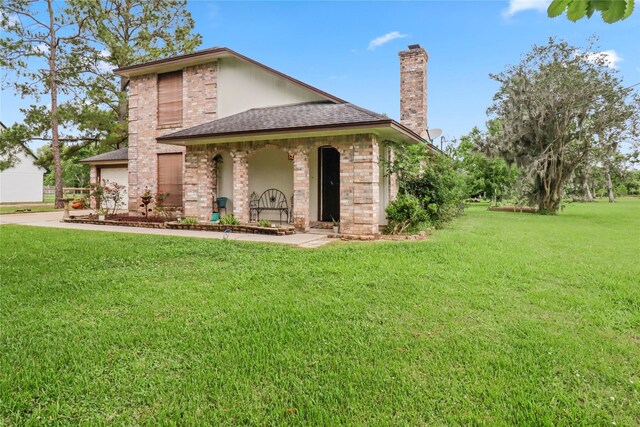 view of front of property with a chimney, a front yard, a shingled roof, and driveway