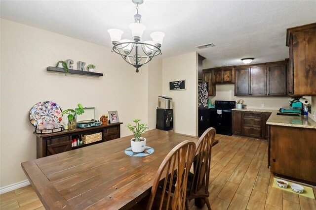 dining area with a chandelier, light wood-style flooring, and baseboards
