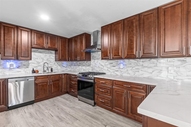 kitchen with stainless steel appliances, wall chimney exhaust hood, a sink, and tasteful backsplash