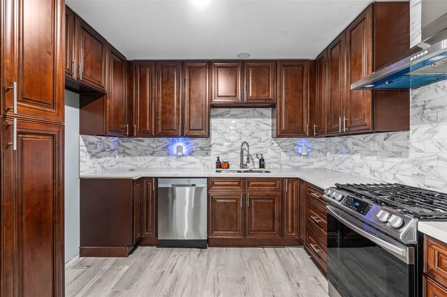 3853 Rosedale St, Houston, TX 77004 - kitchen featuring stainless steel appliances, wall chimney exhaust hood, decorative backsplash, and light wood-type flooring