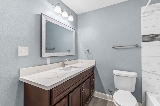bathroom with toilet, wood finished floors, vanity, and baseboards
