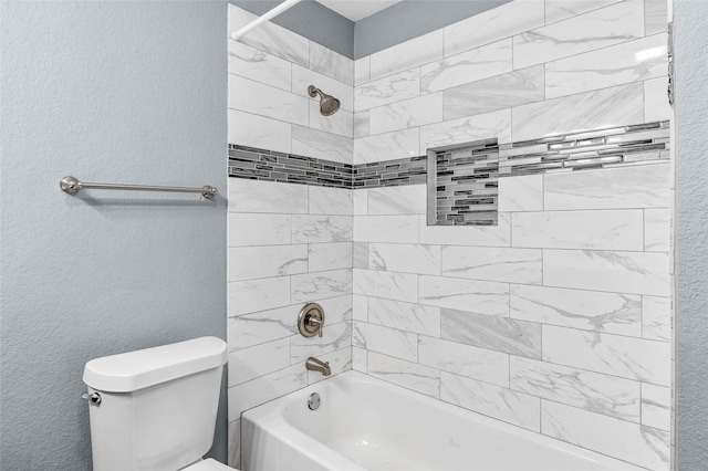 bathroom with bathing tub / shower combination, toilet, and a textured wall