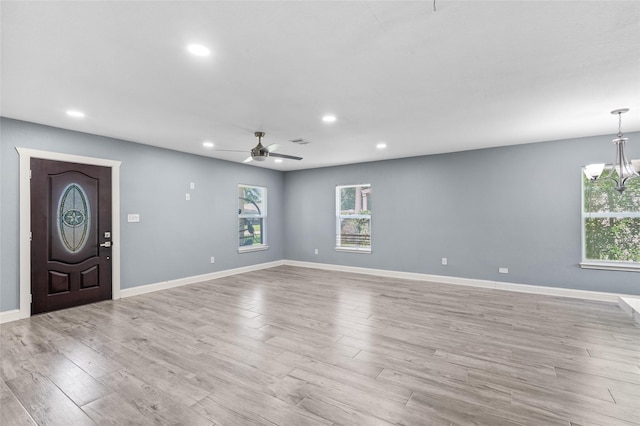 unfurnished living room with recessed lighting, healthy amount of natural light, a ceiling fan, light wood finished floors, and a chandelier