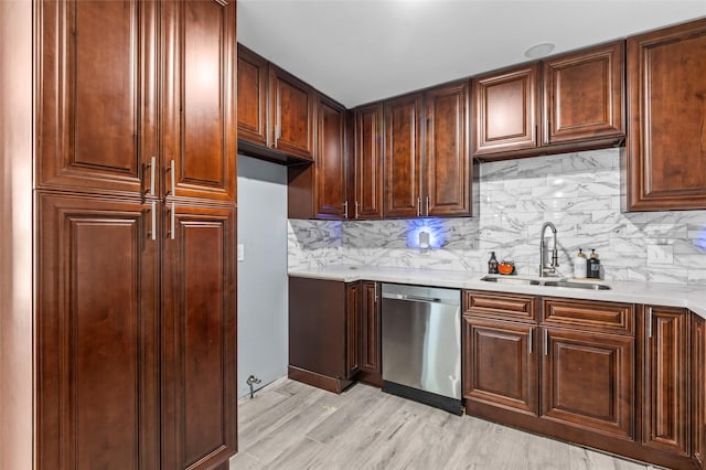 kitchen featuring stainless steel dishwasher, a sink, light countertops, backsplash, and light wood-type flooring