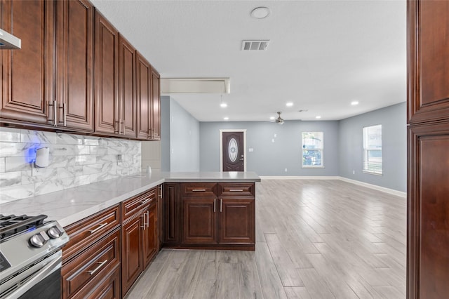 kitchen with decorative backsplash, light wood-style flooring, stainless steel gas range, a peninsula, and open floor plan