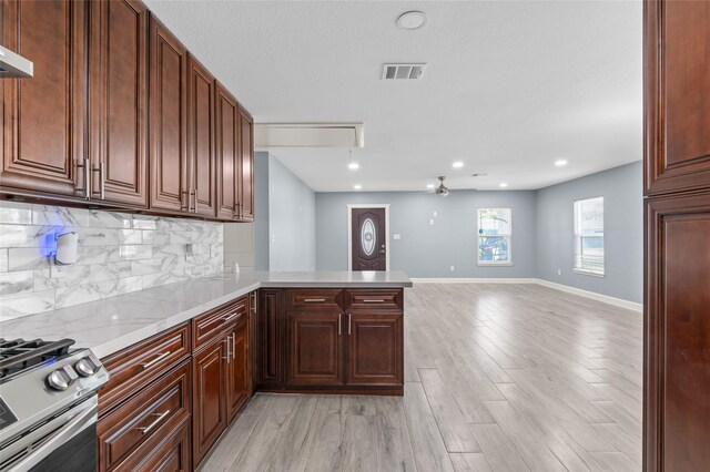 3853 Rosedale St, Houston, TX 77004 - kitchen with stainless steel range with gas stovetop, decorative backsplash, light wood-style floors, a peninsula, and open floor plan