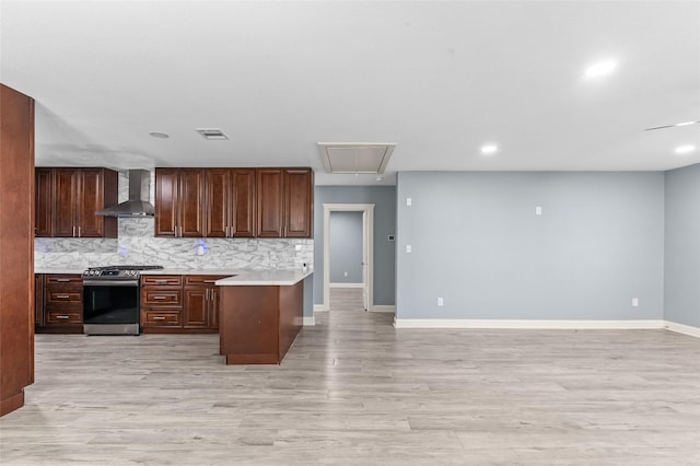 kitchen with stainless steel range with gas stovetop, wall chimney range hood, light countertops, baseboards, and open floor plan