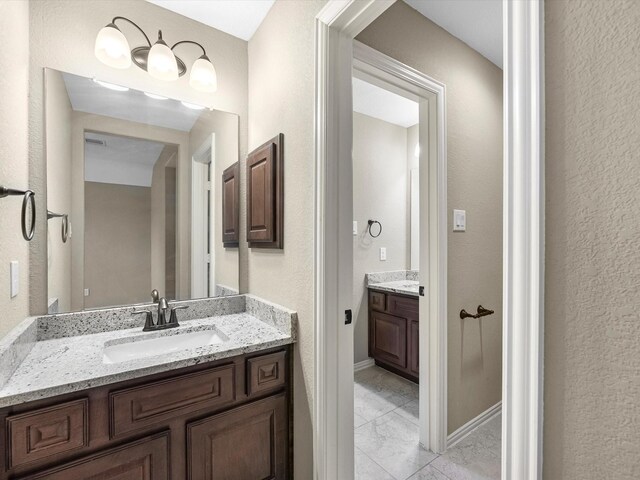 20722 Lavone Dr, Porter, TX 77365 - bathroom featuring marble look tile flooring, two vanities, and a textured wall