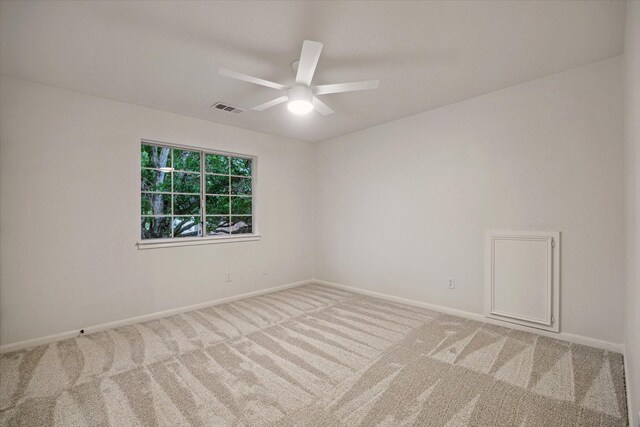 carpeted empty room featuring a ceiling fan and baseboards
