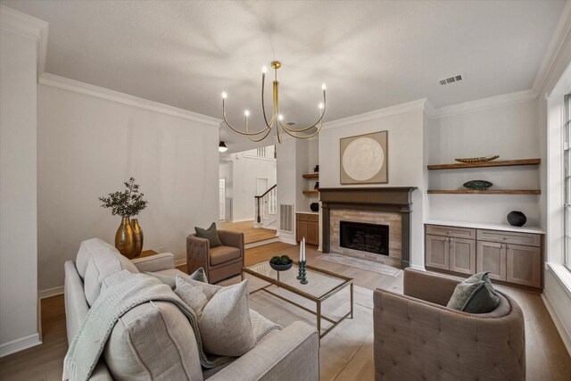 living room featuring a chandelier, ornamental molding, stairway, light wood-type flooring, and built in shelves