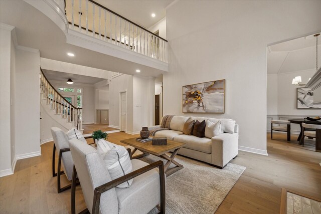 living area featuring light wood-type flooring, baseboards, stairs, and recessed lighting