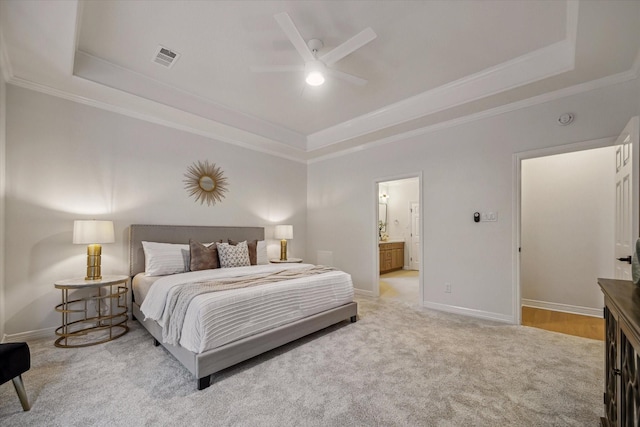 carpeted bedroom featuring a raised ceiling, crown molding, baseboards, connected bathroom, and ceiling fan