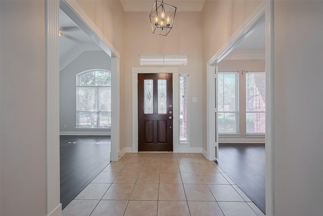 entrance foyer with light tile patterned flooring, a chandelier, and baseboards