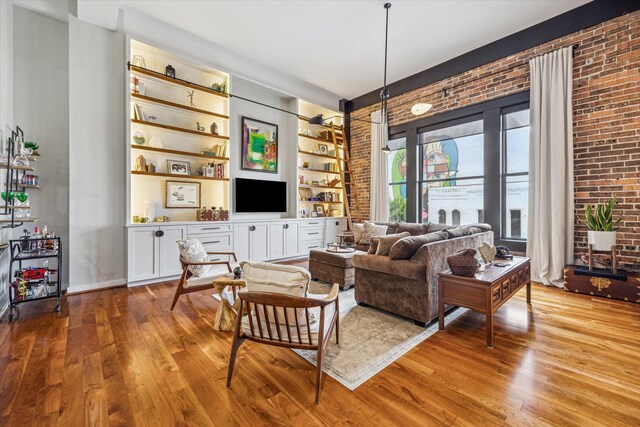 living room with wood finished floors, brick wall, and built in features