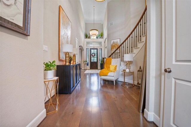 foyer featuring baseboards, a towering ceiling, dark wood-style flooring, and stairs