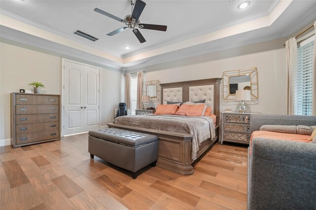 bedroom featuring a tray ceiling, crown molding, light wood finished floors, recessed lighting, and a ceiling fan
