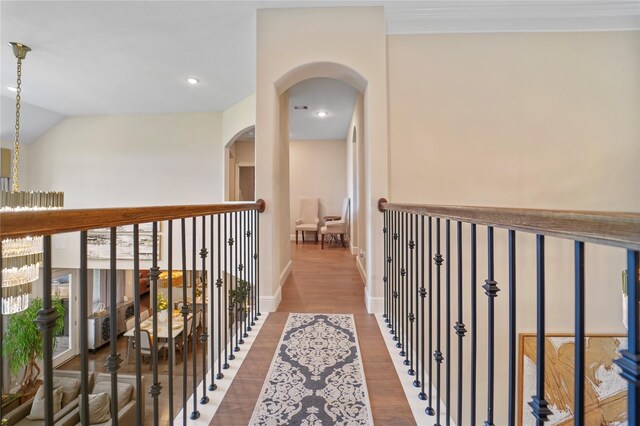 corridor featuring wood finished floors, arched walkways, baseboards, recessed lighting, and lofted ceiling