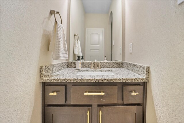 bathroom with a textured wall and vanity