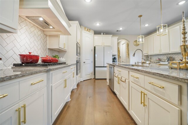 kitchen with a sink, appliances with stainless steel finishes, backsplash, wood finished floors, and recessed lighting