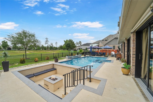 view of swimming pool with a fire pit, a pool with connected hot tub, a patio area, and a fenced backyard