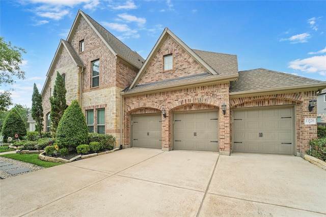 view of front of property with roof with shingles, concrete driveway, a garage, and brick siding