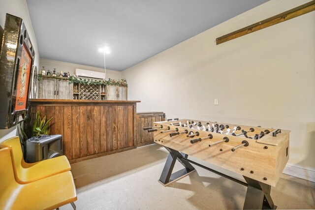 game room featuring a wall mounted AC, a bar, and finished concrete flooring