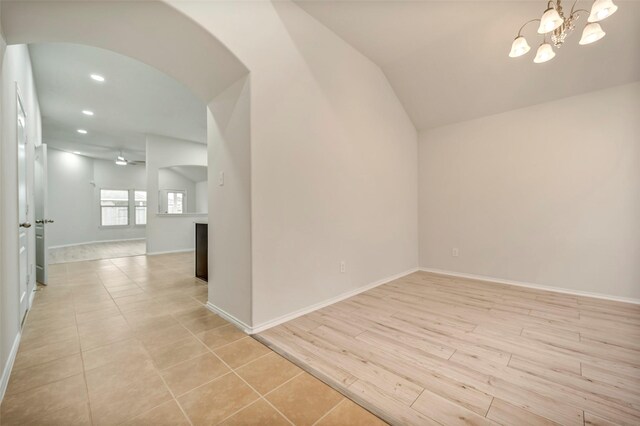 spare room featuring arched walkways, a chandelier, light wood-style flooring, recessed lighting, and baseboards