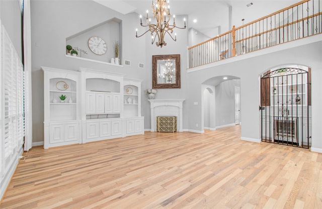 9803 White Rock Lake Trl, Cypress, TX 77433 - unfurnished living room with a high ceiling, arched walkways, a chandelier, baseboards, and light wood finished floors