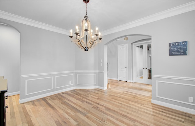 9803 White Rock Lake Trl, Cypress, TX 77433 - unfurnished dining area featuring arched walkways, light wood-style flooring, crown molding, a decorative wall, and a chandelier