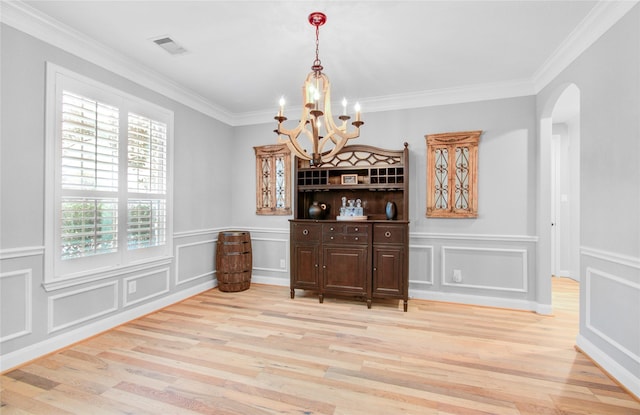 9803 White Rock Lake Trl, Cypress, TX 77433 - dining space with arched walkways, light wood finished floors, a chandelier, ornamental molding, and a decorative wall
