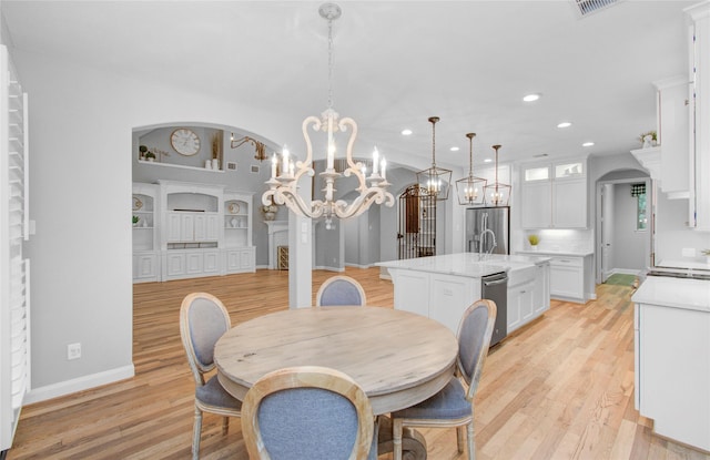 9803 White Rock Lake Trl, Cypress, TX 77433 - dining area featuring a chandelier, recessed lighting, arched walkways, light wood-style floors, and built in features